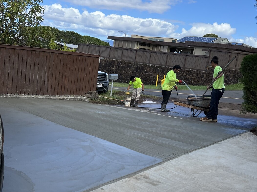 Crew placing and finishing a freshly poured concrete driveway