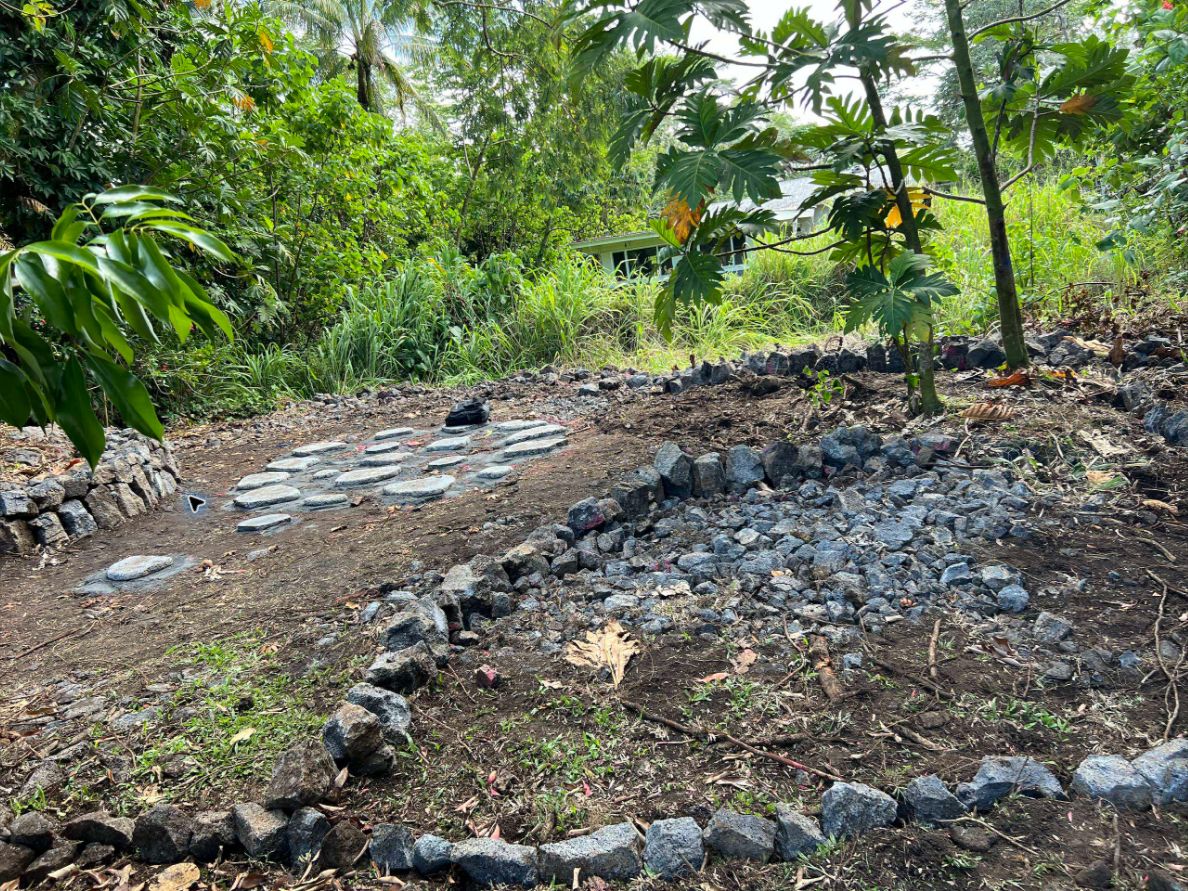 Stone-paving and lava-rock landscape project surrounded by tropical foliage